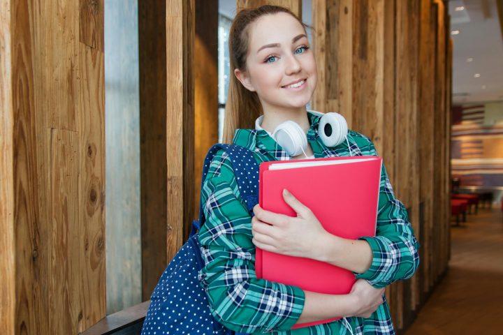 Woman standing in hallway while holding book before class.